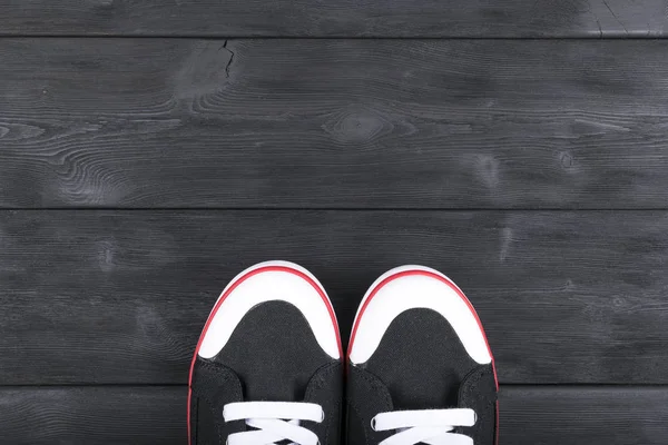 在黑色的木地板上的黑色和白色的鞋子的顶视图。鞋子在一个木制的背景上。在木地板上的运动鞋。体育、 健身、 鞋、 鞋类和对象的概念 — 图库照片