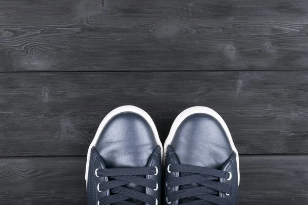 在黑色的木地板上的鞋的顶视图。鞋子在一个木制的背景上。在木地板上的运动鞋。体育、 健身、 鞋、 鞋类和对象的概念 — 图库照片