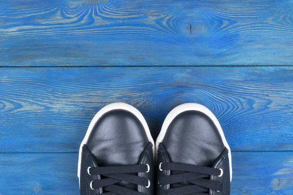 มุมมองเหนือของรองเท้าบนพื้นไม้สีฟ้า รองเท้าบนพื้นหลังไม้ รองเท้าผ้าใบบนพื้นไม้ กีฬา ฟิตเนส รองเท้า รองเท้า และแนวคิดของวัตถุ — ภาพถ่ายสต็อก