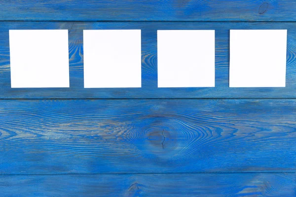 コピー スペースを持つ青い木製テーブルの白い空白のカード。創造的なアラーム、本文、軽いメモ背景の空スペースで机の上の紙の小さなシート, — ストック写真