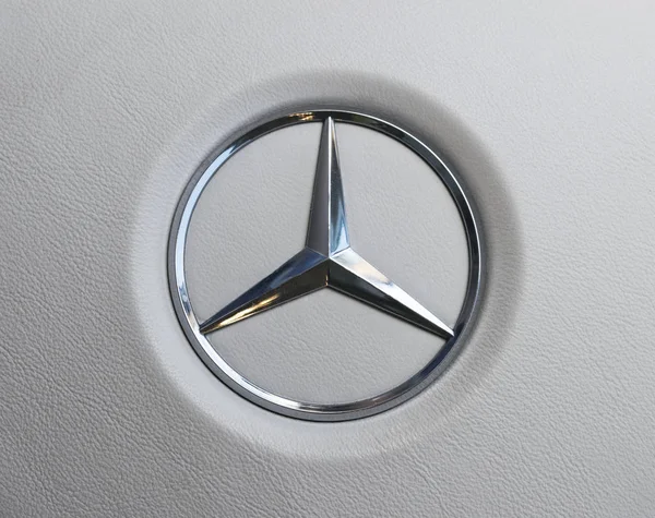 关闭了梅赛德斯-奔驰标志白色皮革方向盘上的视图。现代汽车内部的细节. — 图库照片