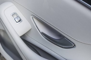 Car white leather interior details of door handle with windows controls and adjustments. Car window controls of modern car. clipart