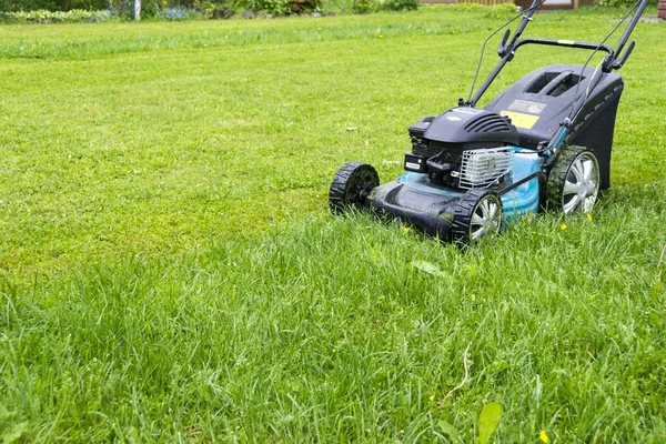 Mowing lawns. Lawn mower on green grass. mower grass equipment. mowing gardener care work tool close up view sunny day