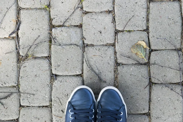Pohled z boty na šedou kamennou zem. Boty na kamenné pozadí. Tenisky na kamenné podlaze. Sportovní fitness boty obuv a objekty koncept — Stock fotografie