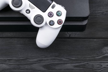 ony Playstation 4 ince 1 tb gözden geçirme ve dualshock oyun kumandası ahşap masa arka plan üzerinde. Home video oyun konsolu