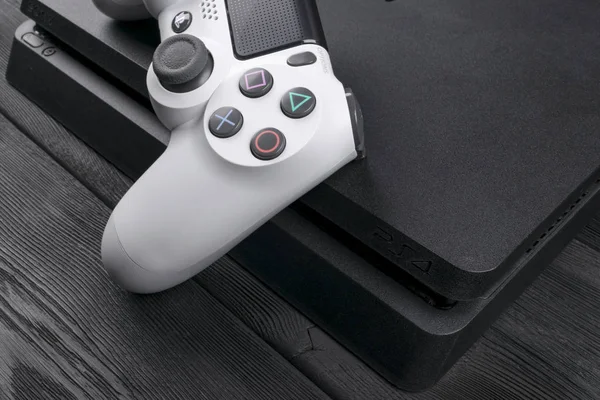 Sony PlayStation 4 Slim 1Tb revisión y controlador de juego de choque dual. Videoconsola con joystick. Inicio Consola de videojuegos sobre fondo de madera —  Fotos de Stock