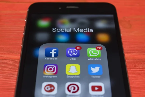 Ekranda kırmızı ahşap masa üzerinde sosyal medya simgeler ile iPhone 7 artı. Smartphone yaşam tarzı smartphone. Başlangıç sosyal medya uygulaması. — Stok fotoğraf