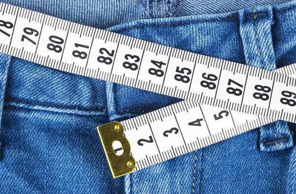 A blue woman jeans and ruler, concept of diet and weight loss. Jeans with measuring tape. Healthy lifestyle, dieting, fitness. Weight control. Successful diet. Reducing excess weight — Stock Photo, Image