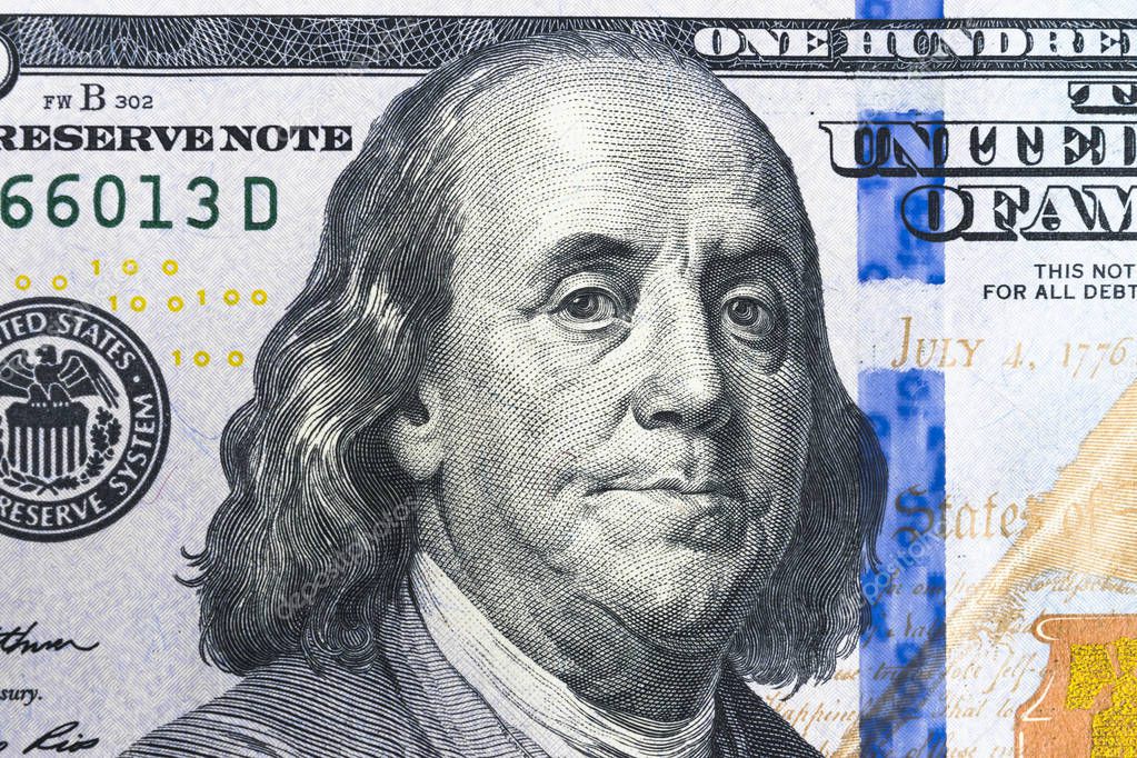 Close up overhead view of Benjamin Franklin face on 100 US dollar bill. US one hundred dollar bill closeup. Heap of one hundred dollar bills on money background.
