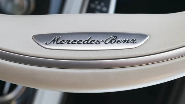 Vue rapprochée d'un logo Mercedes-Benz sur volant en cuir blanc. Détails intérieurs de voiture modernes . — Photo