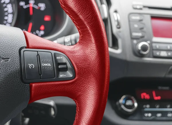 Cruise control buttons on the red steering wheel of a modern car, car interior details — Stock Photo, Image