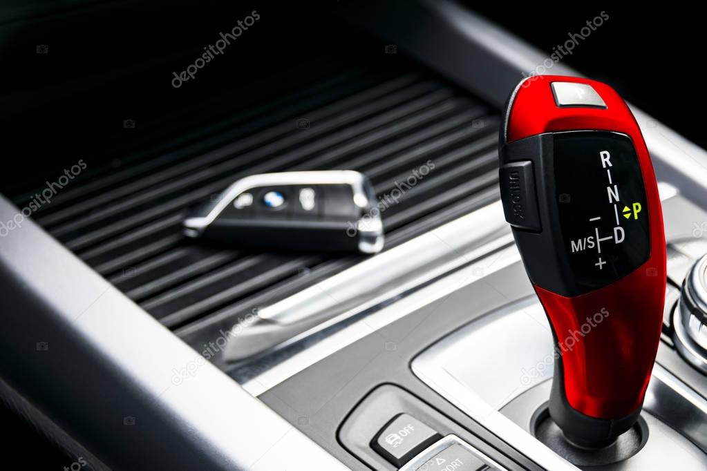 Red automatic gear stick of a modern car, car interior details