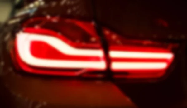 Розмитий фон з червоним заднім світлом на сучасному автомобілі з відображенням. Крупним планом розмитий легкий автомобіль Back Red Tail. М'яка блискавка — стокове фото