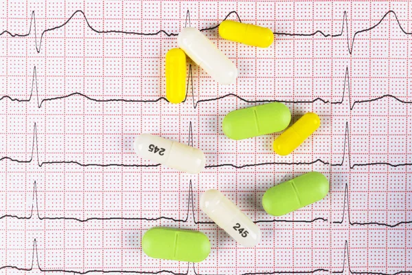 Medical cardiogram chart with pile of pills. Cardiology care health protection prevention and help. Healthy life or insurance concept. EKG, ECG, different pills. — Stock Photo, Image