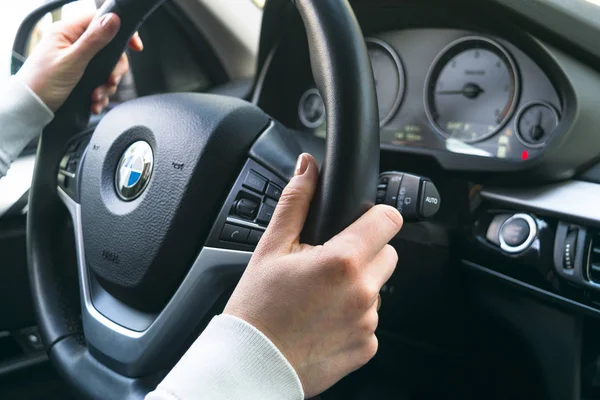Las manos de la mujer en un volante de conducción BMW X5 F15. Manos sosteniendo el volante. Detalles interiores del coche moderno . — Foto de Stock