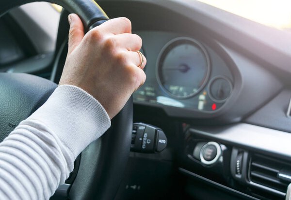 Beautiful Woman's hands on a steering wheel of a modern car. Hands holding steering wheel. Woman driving modern car. Car interior details. Soft lighting.