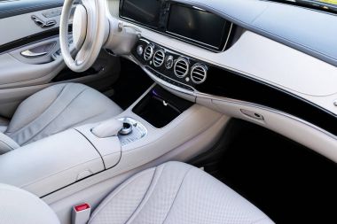 Beyaz deri iç lüks modern araba. Deri rahat beyaz koltuklar ve çoklu ortam. Direksiyon simidi ve gösterge tablosu. Otomatik vites kolu. Modern araba iç detaylar