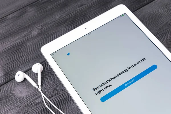Apple iPad Pro y auriculares en la mesa de madera abriendo la página de inicio de la aplicación Twitter. Twitter es una red social en línea y servicio de microblogging. dirigido por Twitter Inc . — Foto de Stock