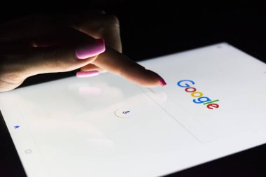  Bir kadın eli tablet bilgisayar ipad Pro ekranda Google arama ana sayfasında arama için geceleri dokunuyor. En popüler Internet arama Google olduğunu