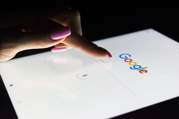 Die Hand einer Frau berührt nachts den Bildschirm des Tablet-Computers ipad pro, um auf der Google-Suchseite zu suchen. Google ist die beliebteste Internet-Suche — Stockfoto