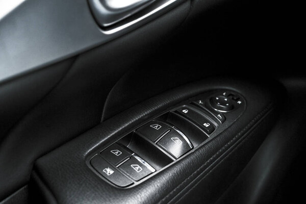 Автомобиль черный перфорированный кожаные детали интерьера дверной ручки с окнами управления и регулировки. Рукоятка двери автомобиля внутри роскошного современного автомобиля. Управление кнопкой переключения
