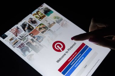 Sankt-Petersburg, Rusya, 21 Aralık 2017: Bir kadın eli Apple ipad Pro Internet hizmet Pinterest üstünde belgili tanımlık perde ile gece dokunuyor. Tablet bilgisayar ekranında Pinterest uygulama.