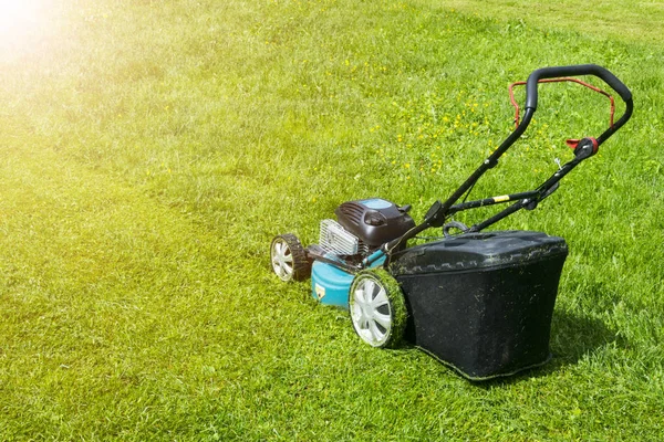 Mowing lawns. Lawn mower on green grass. mower grass equipment. mowing gardener care work tool close up view sunny day. Soft lighting
