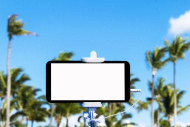 Selfie monopod sopayla cep telefonu, tropikal arka plan, metin, beyaz ekran için boş alan