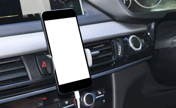 Smartphone in a car use for Navigate or GPS. Driving a car with Smartphone in holder. Mobile phone with isolated white screen. Blank empty screen. copy space. Empty space for text. modern car interior details.