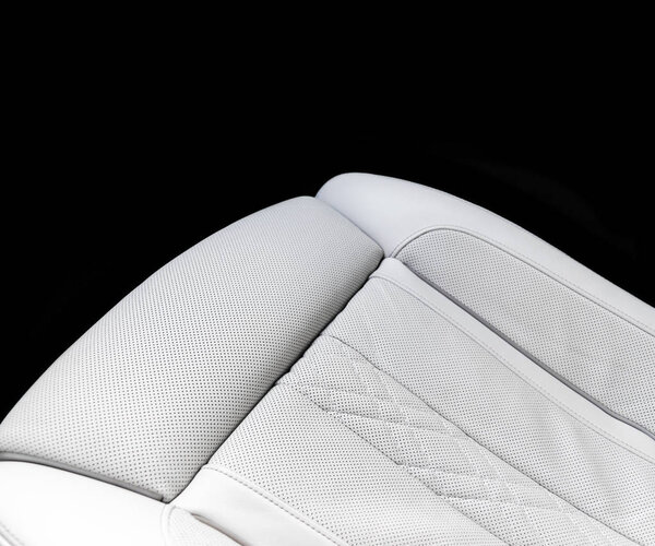 Белый кожаный интерьер роскошного современного автомобиля. Перфорированная белая кожа интерьера роскошного современного автомобиля. Перфорированные белые кожаные удобные сиденья с прострочкой на черном фоне. Современные детали интерьера автомобиля. Детализирую машину. Машина i
