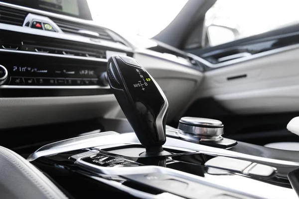 Automatic gear stick of a modern car. Modern car interior details. Close up view. Car detailing. Automatic transmission lever shift. White leather interior with stitching.