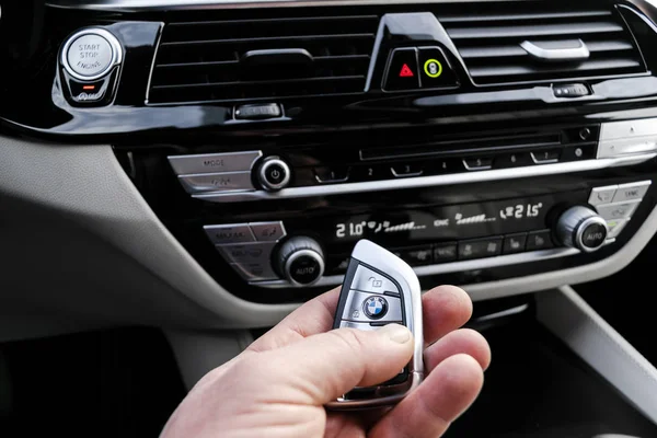 La mano del hombre sostiene una llave inalámbrica del coche de BMW 650i 2019 en el interior del coche de cuero blanco. Detalles interiores del coche moderno . — Foto de Stock