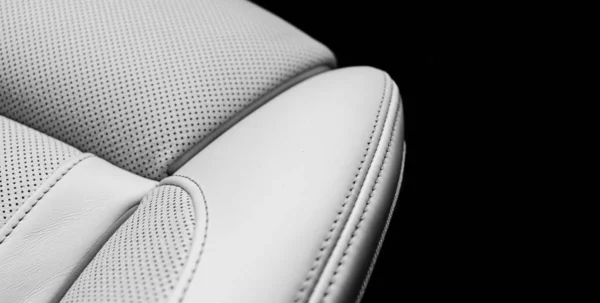 Белый кожаный интерьер роскошного современного автомобиля. Перфорированные белые кожаные удобные сиденья с прострочкой на черном фоне. Современные детали интерьера автомобиля. Детализирую машину. Машина внутри — стоковое фото