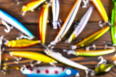 Balıkçılık malzemeleriyle geçmişi bulanık. Tahtada odağını kaybetmiş olta takımı ve yalpalayıcı. Balık kancaları, yemler ve yemler. Bulanık balık takımları karanlık bir masada.