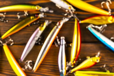 Balıkçılık malzemeleriyle geçmişi bulanık. Tahtada odağını kaybetmiş olta takımı ve yalpalayıcı. Balık kancaları, yemler ve yemler. Bulanık balık takımları karanlık bir masada.