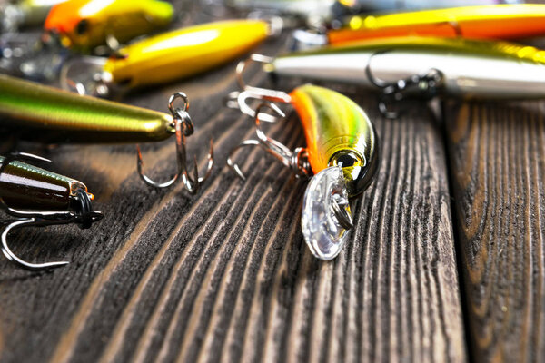 Fishing tackle background. Fishing tackles and wobbler on wooden board. Fishing hooks, lures and baits. Fishing gear on a dark table