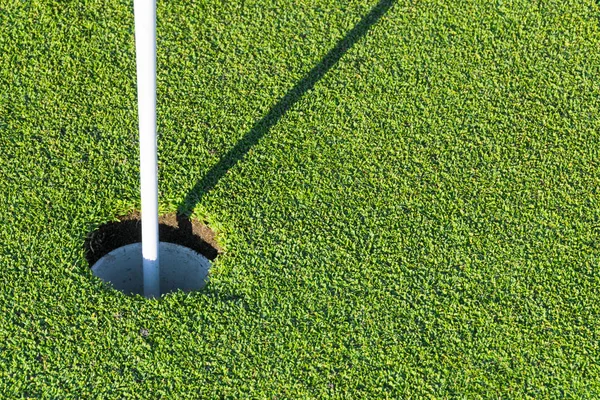 Γκολφ τρύπα με σημαία στο πράσινο γρασίδι του γηπέδου γκολφ. Άποψη της τρύπας του γκολφ στο πράσινο πεδίο. Παίζοντας γκολφ — Φωτογραφία Αρχείου