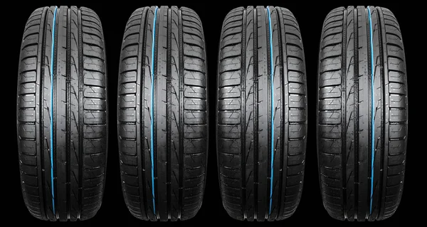 Studio shot of a set of summer car tire isolated on black background. Tire stack. Car tyre protector close up. Black rubber tire. Brand new car tires. Close up black tyre profile. Car tires in a row