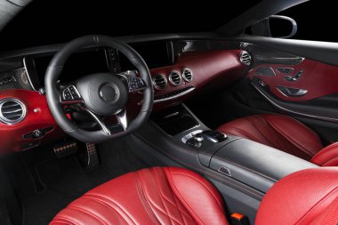 Kırmızı lüks modern araba. Direksiyon simidi, vites kolu ve gösterge paneli var. Kesme yolu. Modern araba iç dekorasyonunun ayrıntıları. Otomatik vites kolu. Pahalı bir arabaya dikilmiş deri koltuklar.