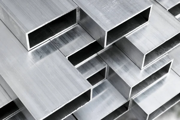 Profil aluminiowy do produkcji okien i drzwi. Konstrukcyjne metalowe kształty aluminium. Konstrukcja profili aluminiowych. Konstrukcje aluminiowe tło fabryczne. — Zdjęcie stockowe