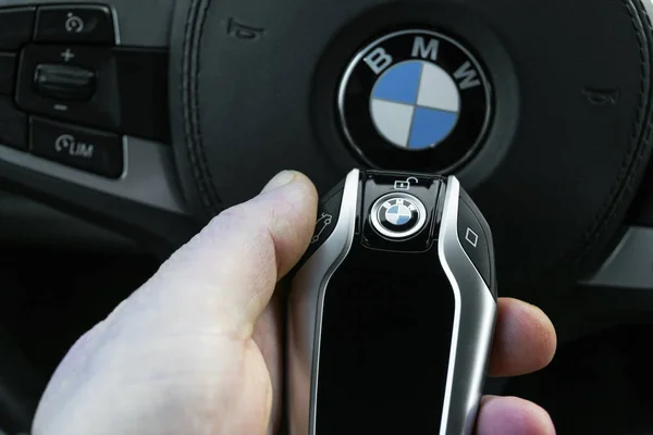 Мужская рука держит беспроводной BMW 640i GT 2019 автомобиль ключ в белой кожаной салоне автомобиля. Современный автомобиль детали интерьера . — стоковое фото