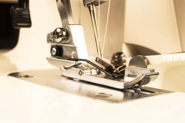 Dikiş makinesinin ayaklarına iğne ve iplik batır. Dikiş makinesinin ayrıntıları. Dikiş makinesinin ayağı iğneyle. Üretim hattı dikiş makinesi. İğne ve ayak izi detayı. 