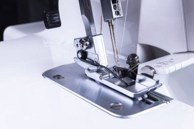 Presser foot of sewing machine with needle and thread close up. Detail of sewing machine. The sewing machine's foot with a needle. Production line sewing machine. Needle and footstep detail.  clipart