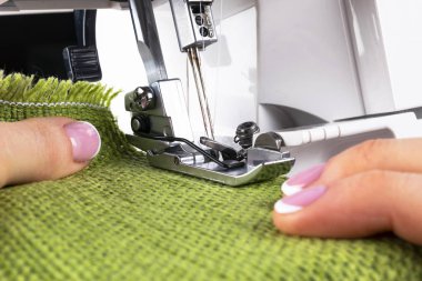 Dikiş makinesinin ayaklarına iğne ve iplik batır. Kadın parmaklı dikiş makinesinin ayrıntıları. Kadın eli dikiş. Üretim hattı dikiş makinesi. İğne ve ayak izi detayı.