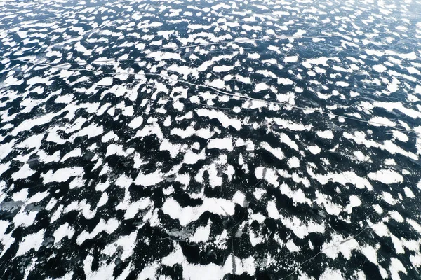 Aerial view of a frozen lake surface. Aerial Snow pattern on the frozen lake. Frozen lake ice captured with a drone. Aerial photography. Winter snow texture
