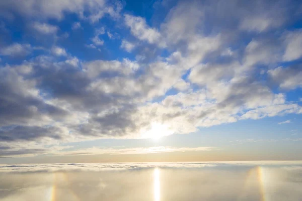 Luftaufnahme Weiße Wolken am blauen Himmel mit Sonnenhalo. Ansicht von oben. Blick aus der Drohne. aus der Vogelperspektive. Luftaufnahme von oben Wolkenlandschaft. Beschaffenheit der Wolken. Blick von oben. Sonnenaufgang oder Sonnenuntergang über Wolken — Stockfoto