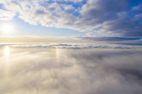 Aerial view White clouds in blue sky with solar halo. Top view. View from drone. Aerial bird\'s eye view. Aerial top view cloudscape. Texture of clouds. View from above. Sunrise or sunset over clouds