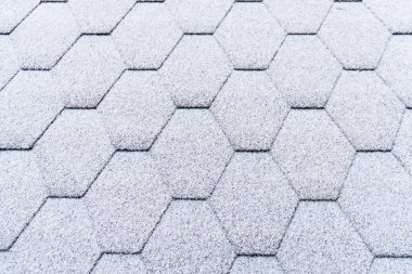 Asfalt çatı kiremitleri hafif karla kaplı. Tavan kiremitleri buzla kaplı. Evin çatısı karla kaplı.. 