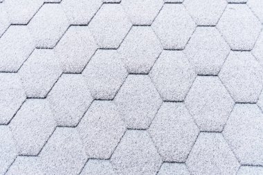 Asfalt çatı kiremitleri hafif karla kaplı. Tavan kiremitleri buzla kaplı. Evin çatısı karla kaplı..