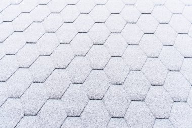 Asfalt çatı kiremitleri hafif karla kaplı. Tavan kiremitleri buzla kaplı. Evin çatısı karla kaplı..